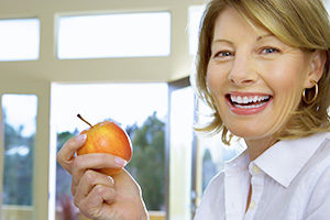 Woman Smiling with Dentures and Apple